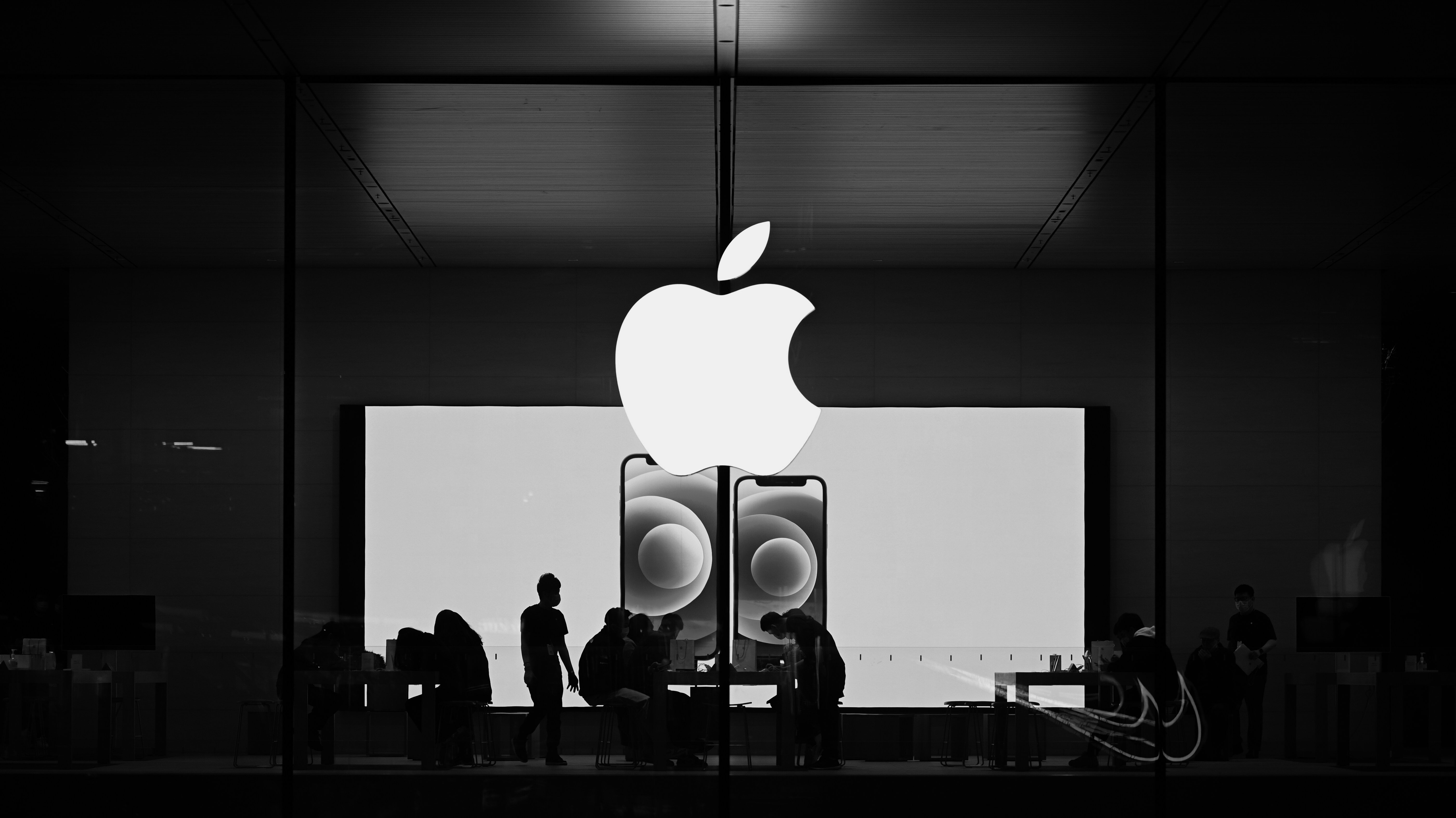 Black and white image of an Apple Store. The sleek minimal design runs throughout the brands products and storefronts adding to its brand equity. 